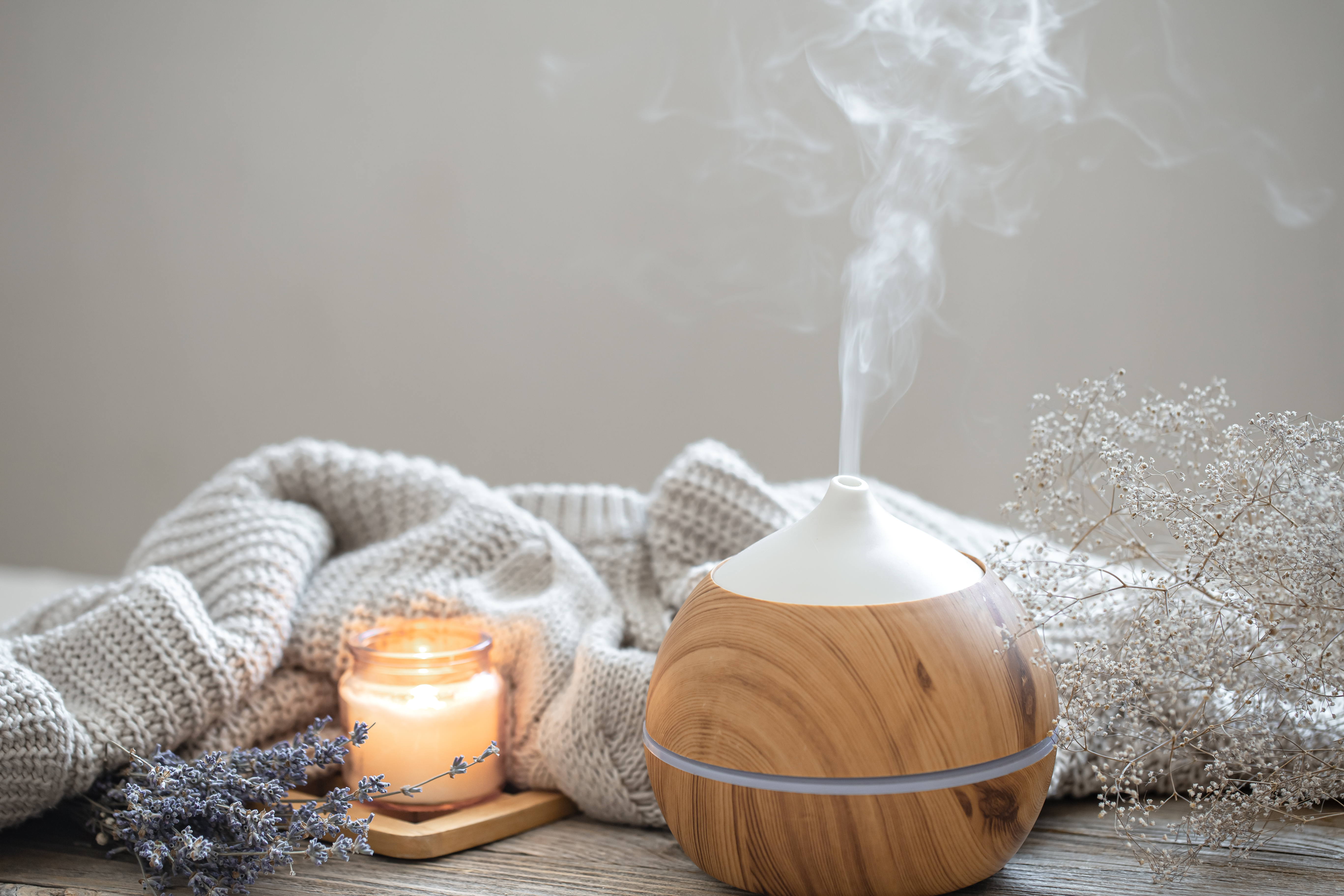 Cozy home composition with air humidifier, knitted element, lavender and candle copy space.